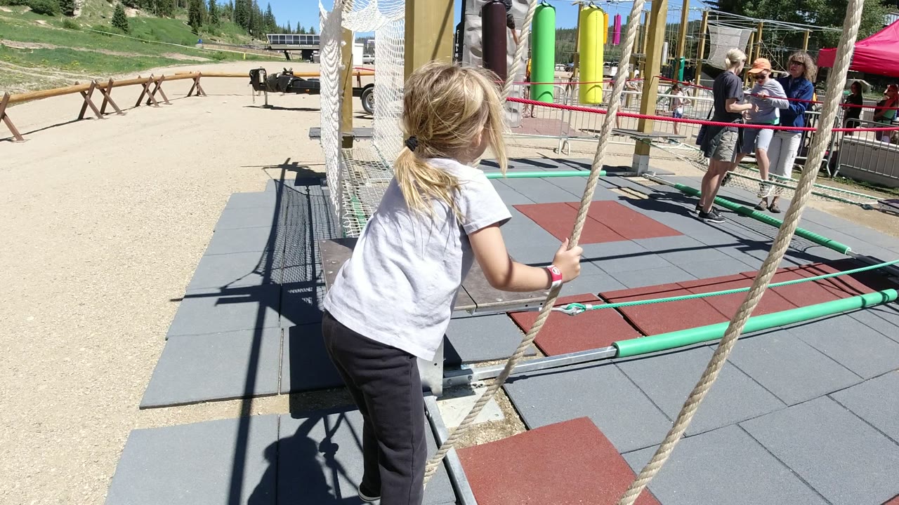Young girl holding ropes on an outdoor balance course.