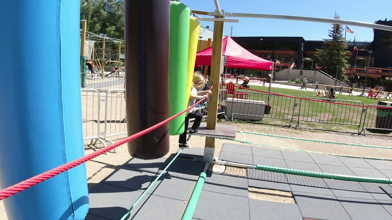 Colorful playground ropes and padded posts with a child partly visible.