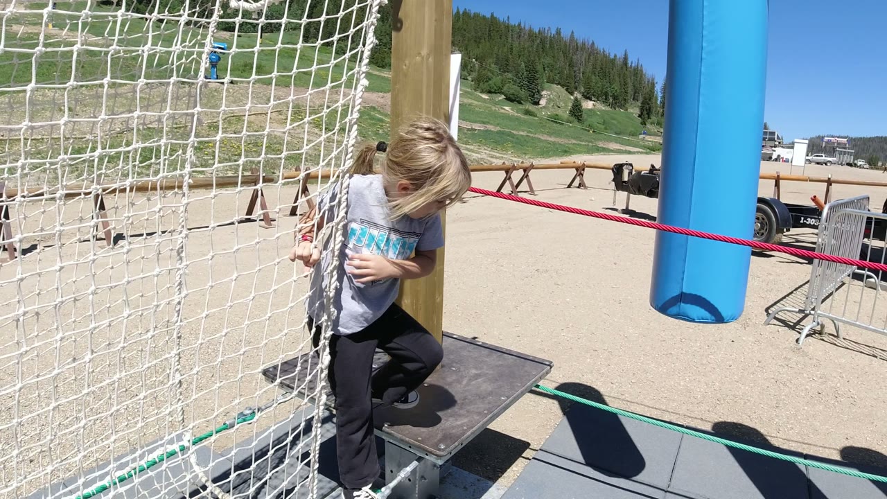 Girl holding a red rope beside white obstacle netting.