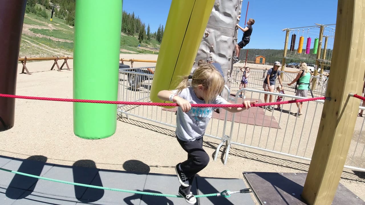 Child holding a red rope on an outdoor play structure.