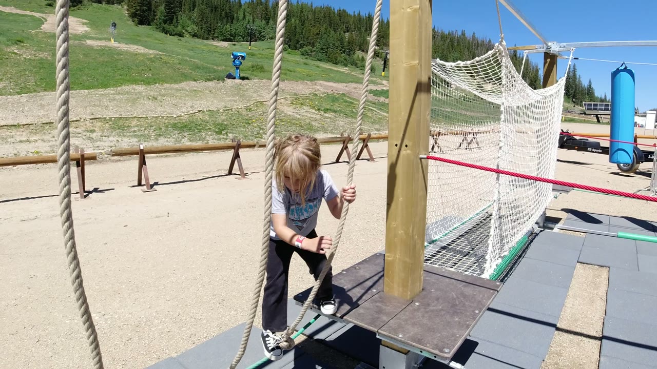 Child holding ropes on an outdoor playground platform