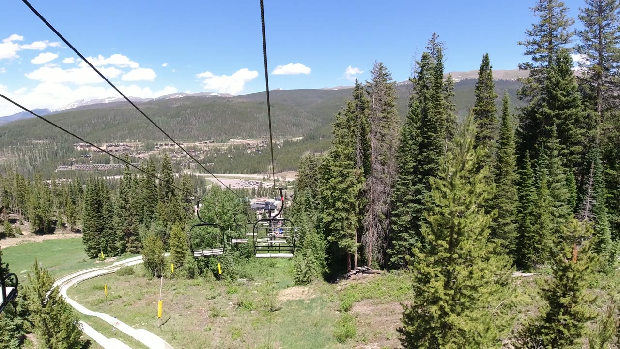 Chairlift cables over evergreen trees and distant mountains.