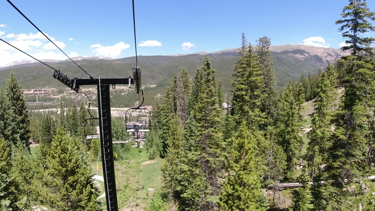 Chairlift cables and towers above green mountain forest.