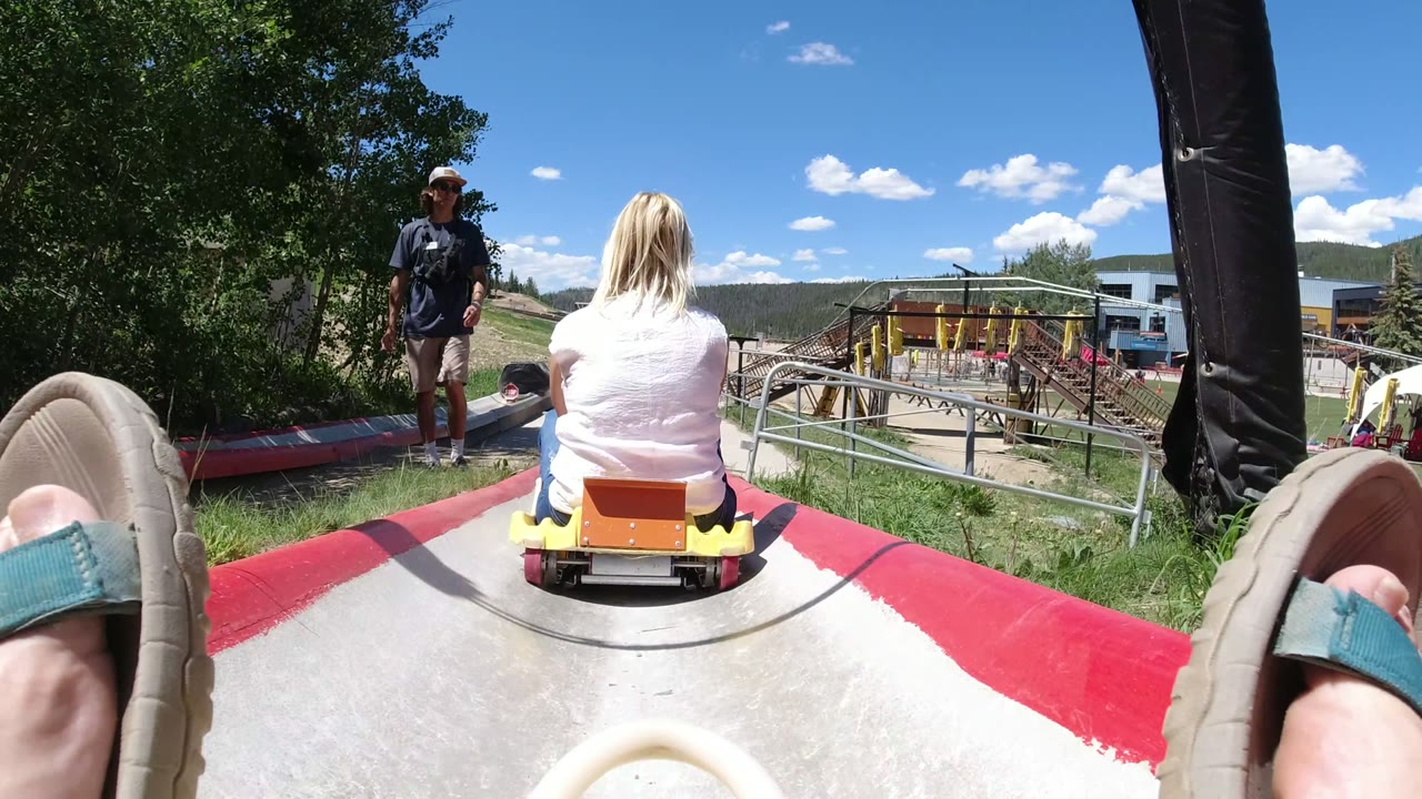 Seated rider view behind a woman on a yellow slide cart.