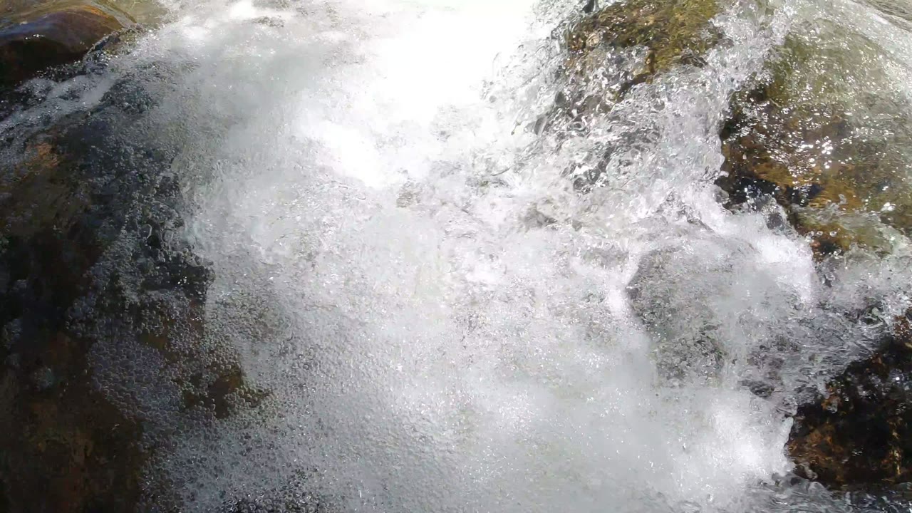 Whitewater spreads across smooth green-brown rock in Winter Park, Colorado, with a darker channel visible near the upper right and no visible people.