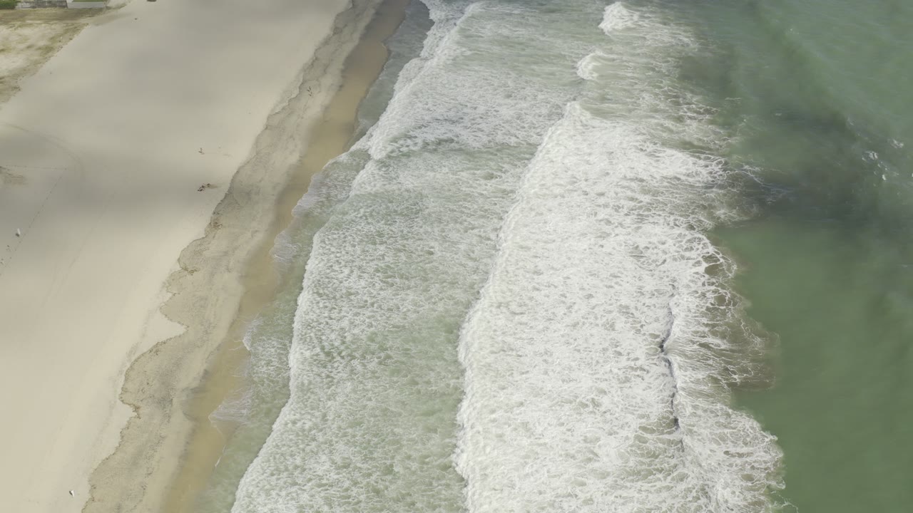 White surf breaking beside pale beach sand