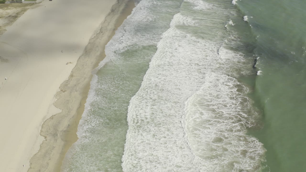Aerial view of waves breaking along a sandy beach.