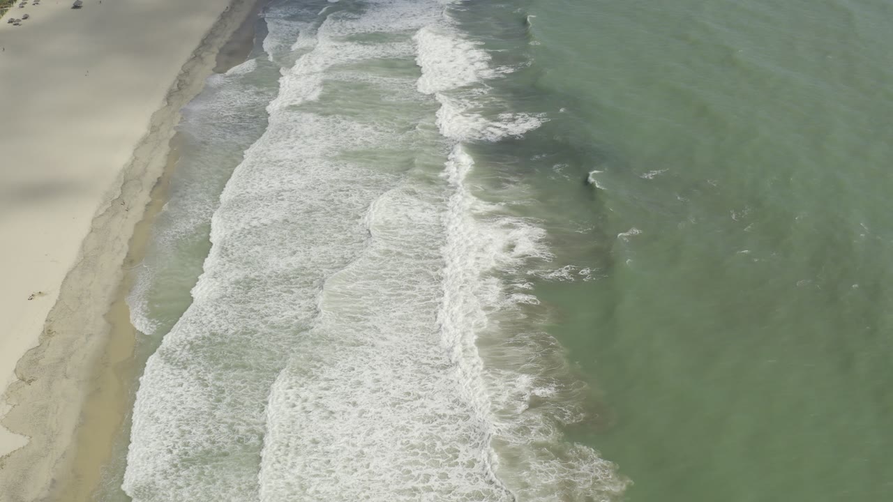 Diagonal beach edge with waves spreading across shallow water.