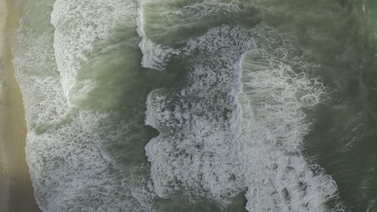 Top-down waves forming four pale layers near the shoreline.