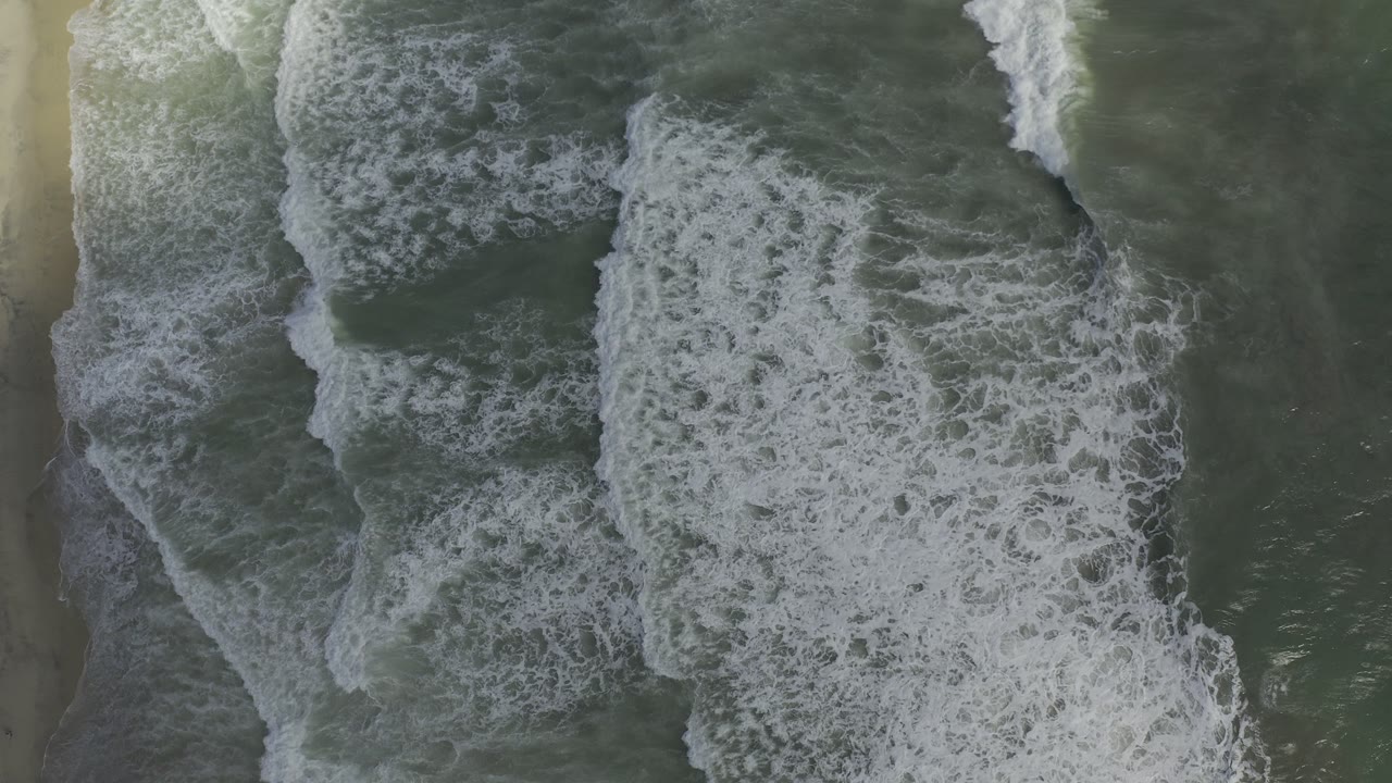 Foamy surf bands overlap in green coastal water.