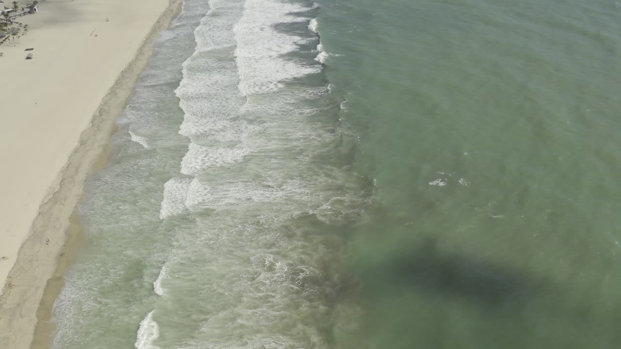 Overhead Los Cabos, Mexico frame showing stronger whitewater bands moving toward the sand, with open green sea filling the right side and no visible people.