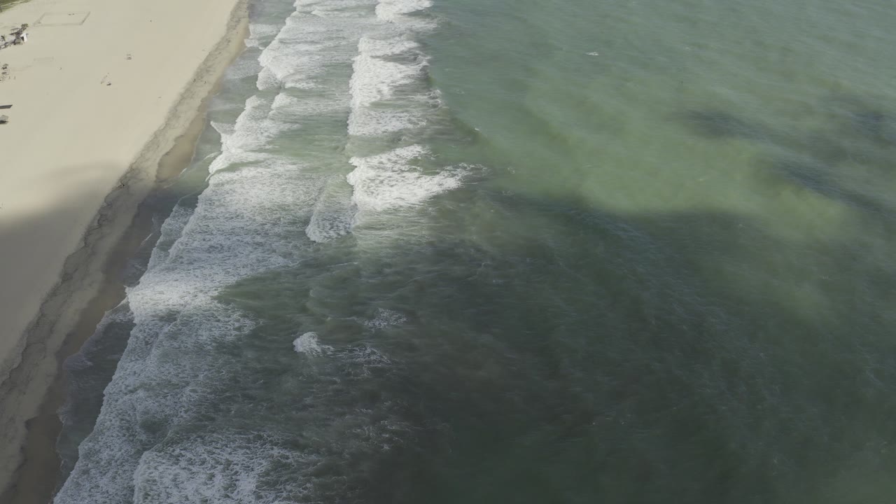 Aerial shoreline with broken white waves and green sea