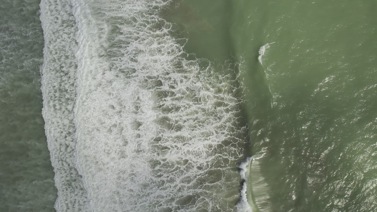 Top-down green sea with surf foam shifted toward the left side