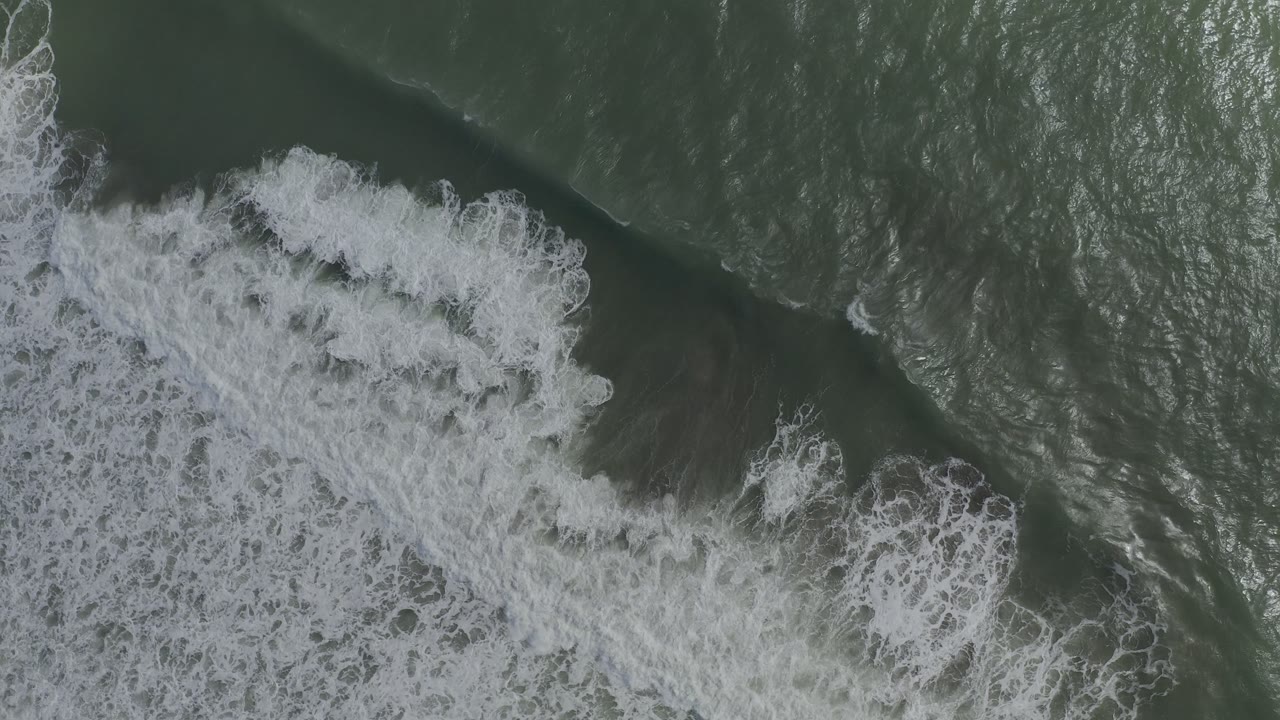 Dense white foam churns over dark green water from a top-down angle.