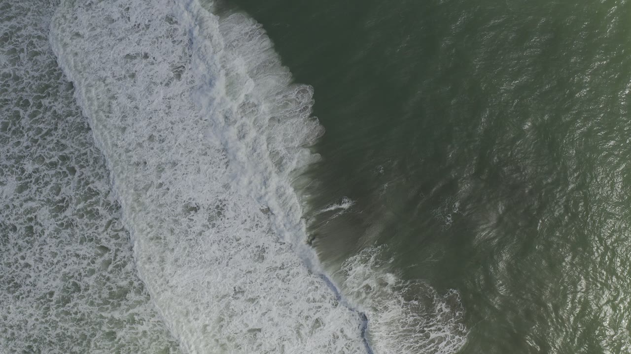 Overhead green ocean water with a white surf band at left.