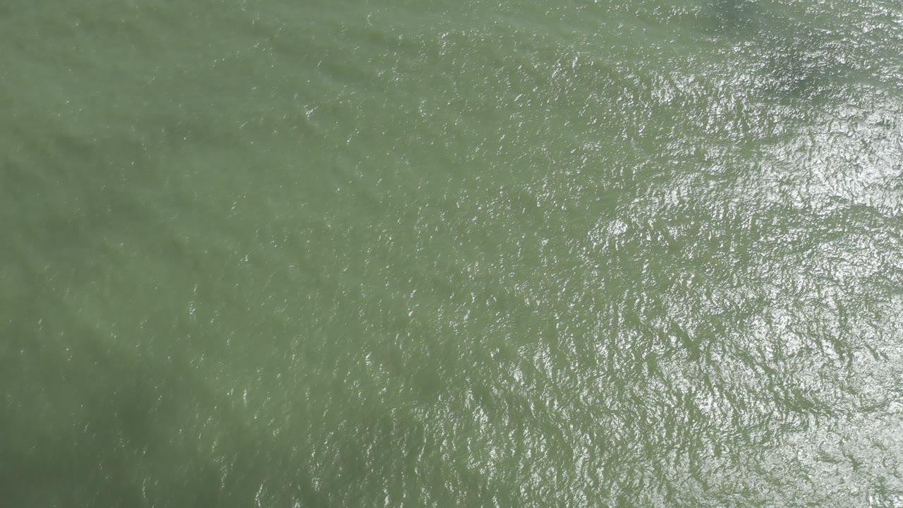 Sun glints across green ocean water in Los Cabos, Mexico, with small ripples filling the frame and no visible people.