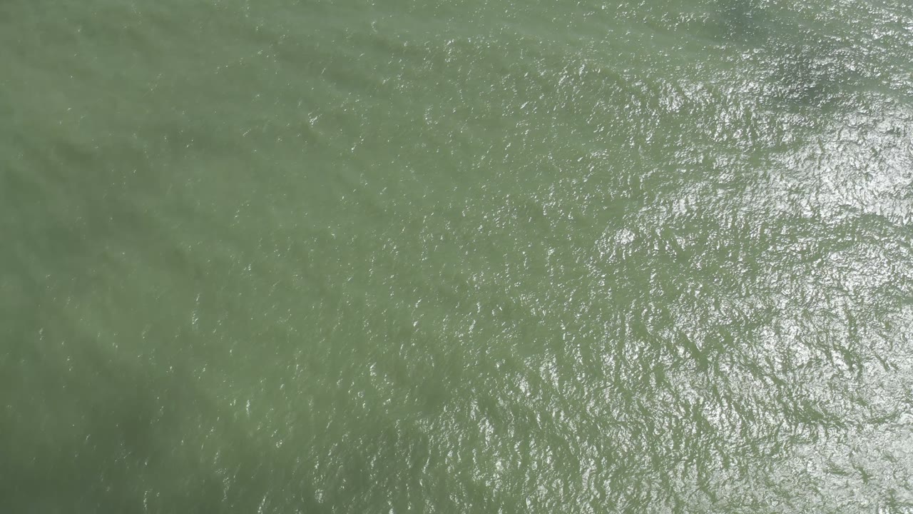 Ruffled green-blue seawater in Los Cabos, Mexico fills the frame, with scattered bright highlights and no visible people.