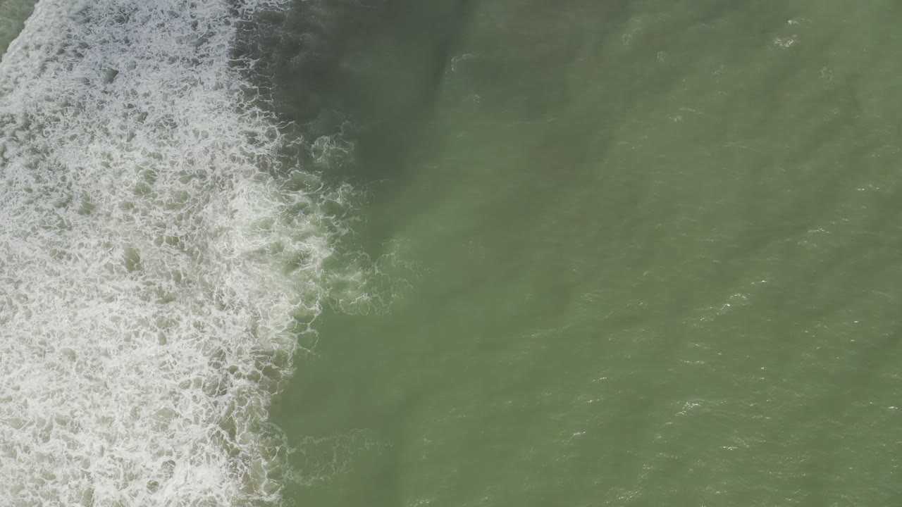 Green ocean surface with white wave foam near the left center.