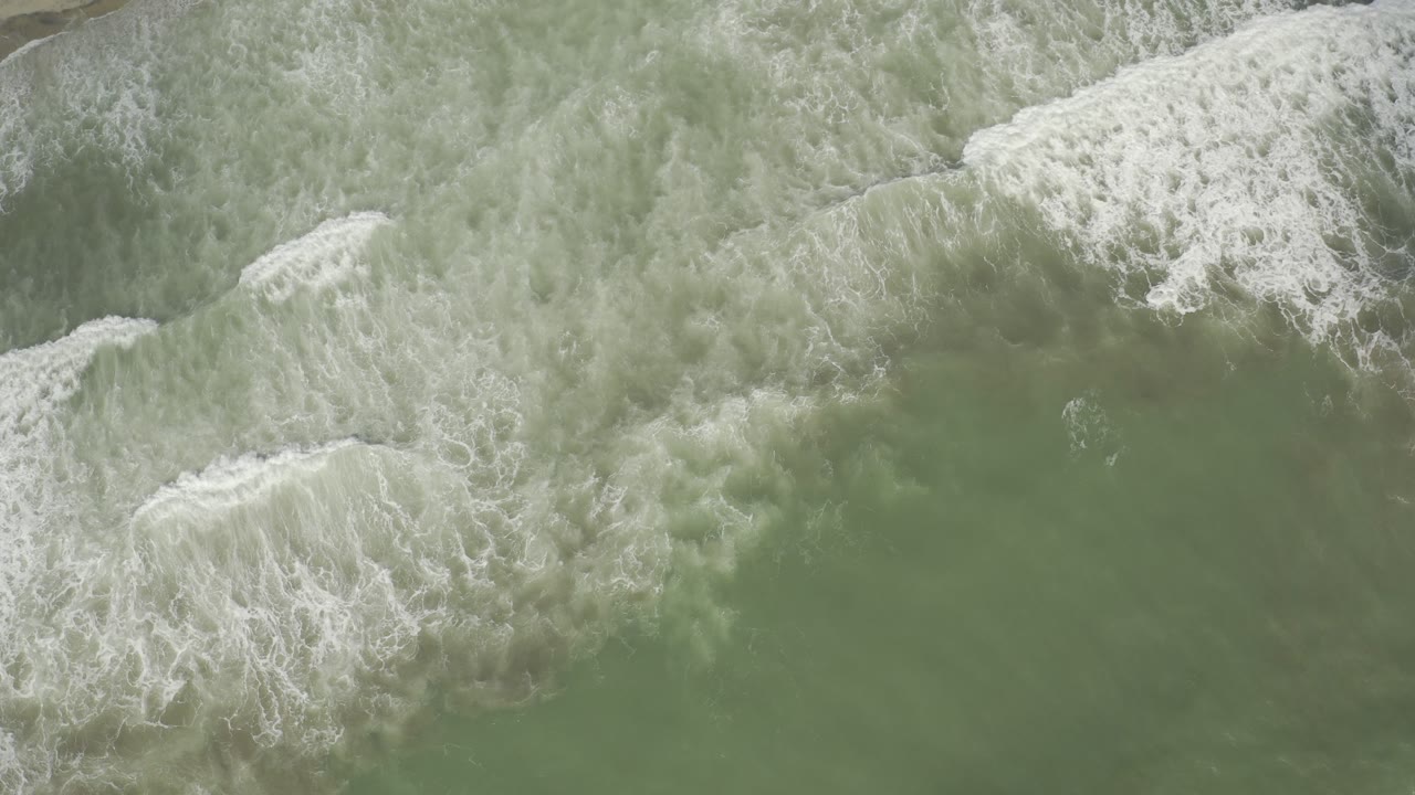 Foamy wave break over muted green water