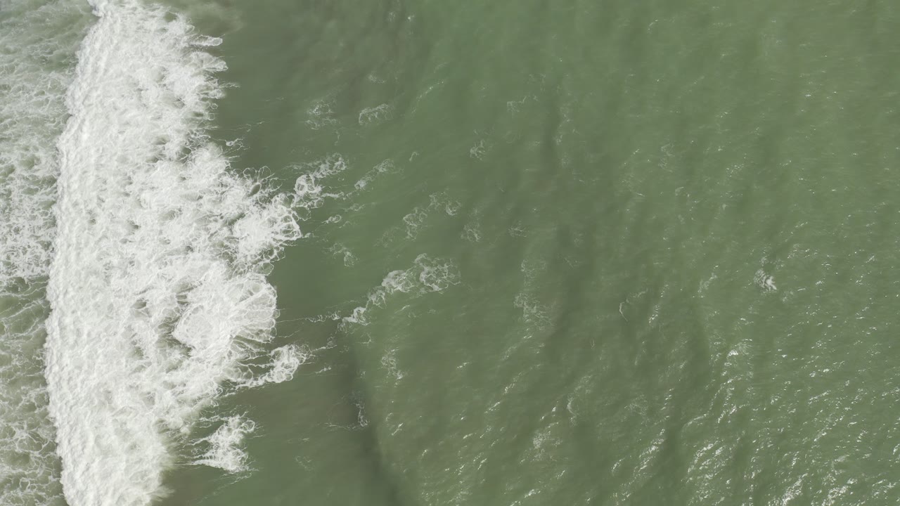 Overhead surf line breaking across green ocean water
