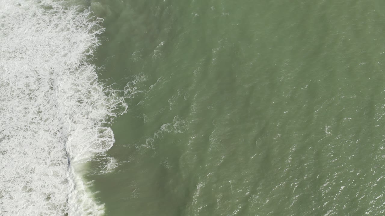 Overhead green ocean water with white surf entering from the left.