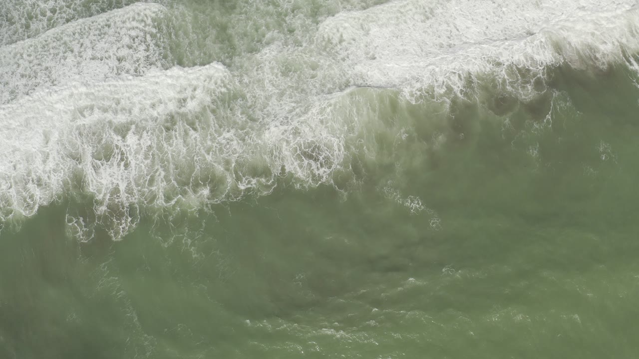 Overhead view of green ocean water and white breaking surf in Los Cabos, Mexico, with no visible people.