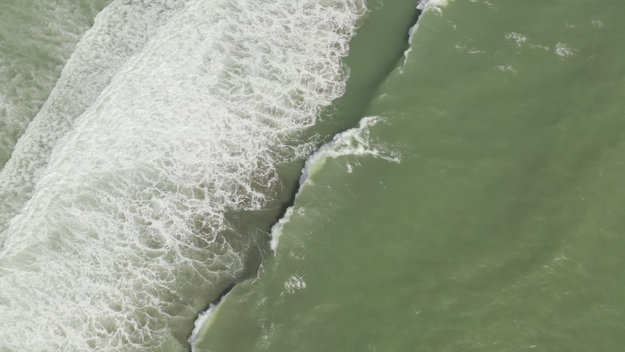 Overhead Los Cabos frame with foamy whitewater running diagonally through green sea, leaving open water on the right and no visible people.