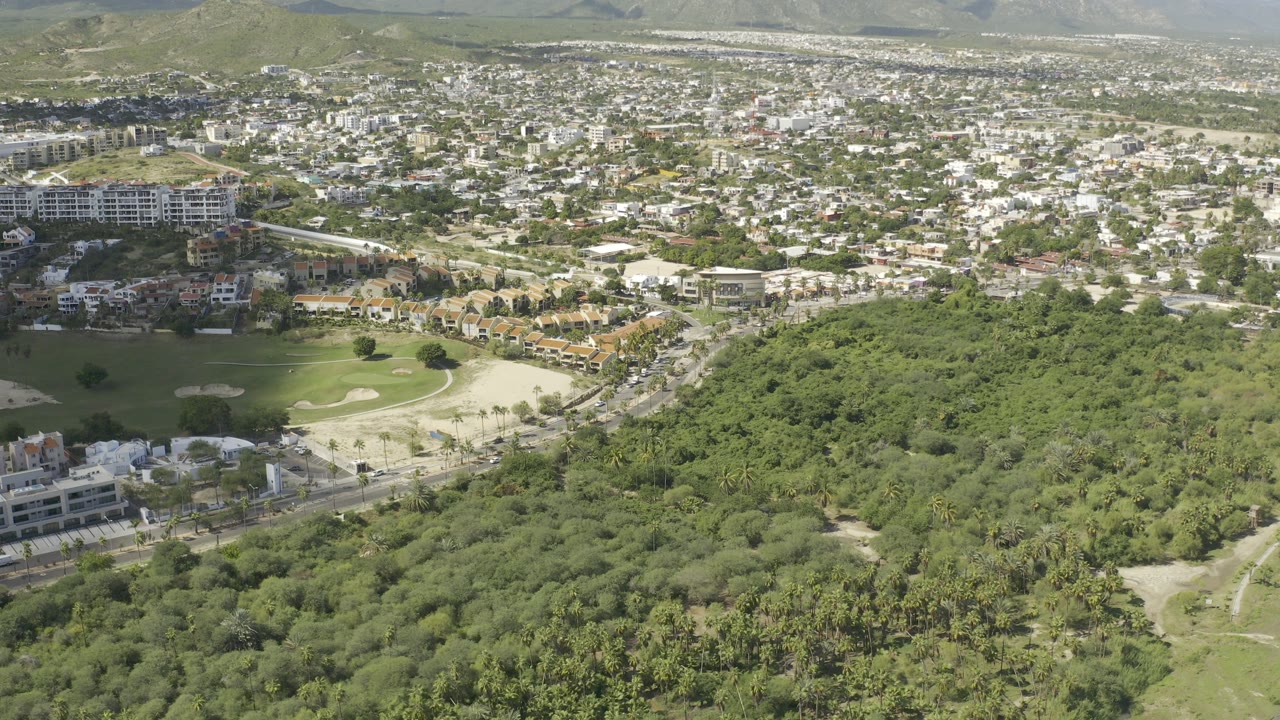 Aerial view of trees, golf course, roads, and hillside homes.