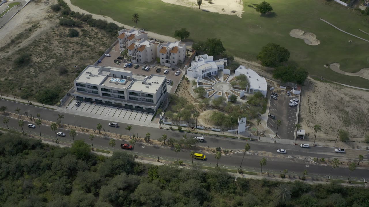 Aerial view of road traffic near buildings and golf greens.