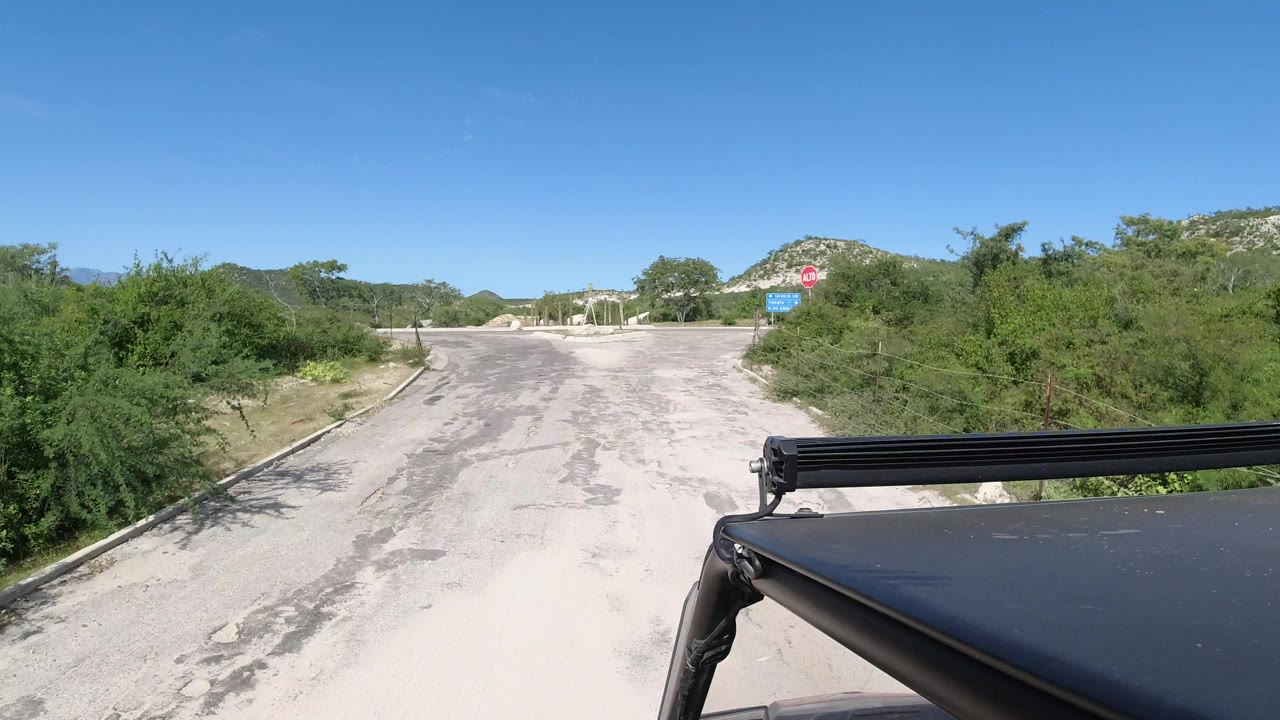 Empty paved road leading toward a stop sign and desert hills.
