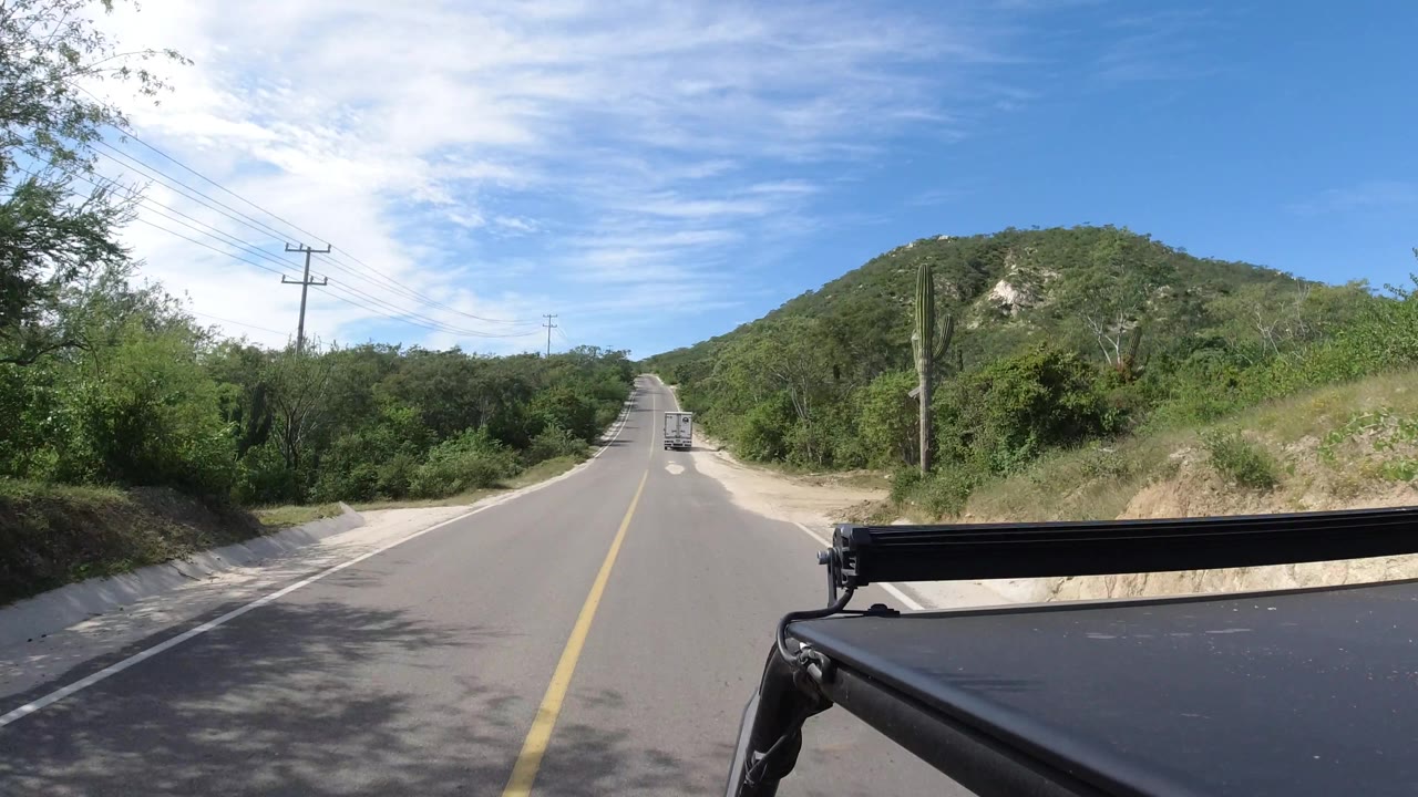 Curving rural road with utility poles and hillside brush