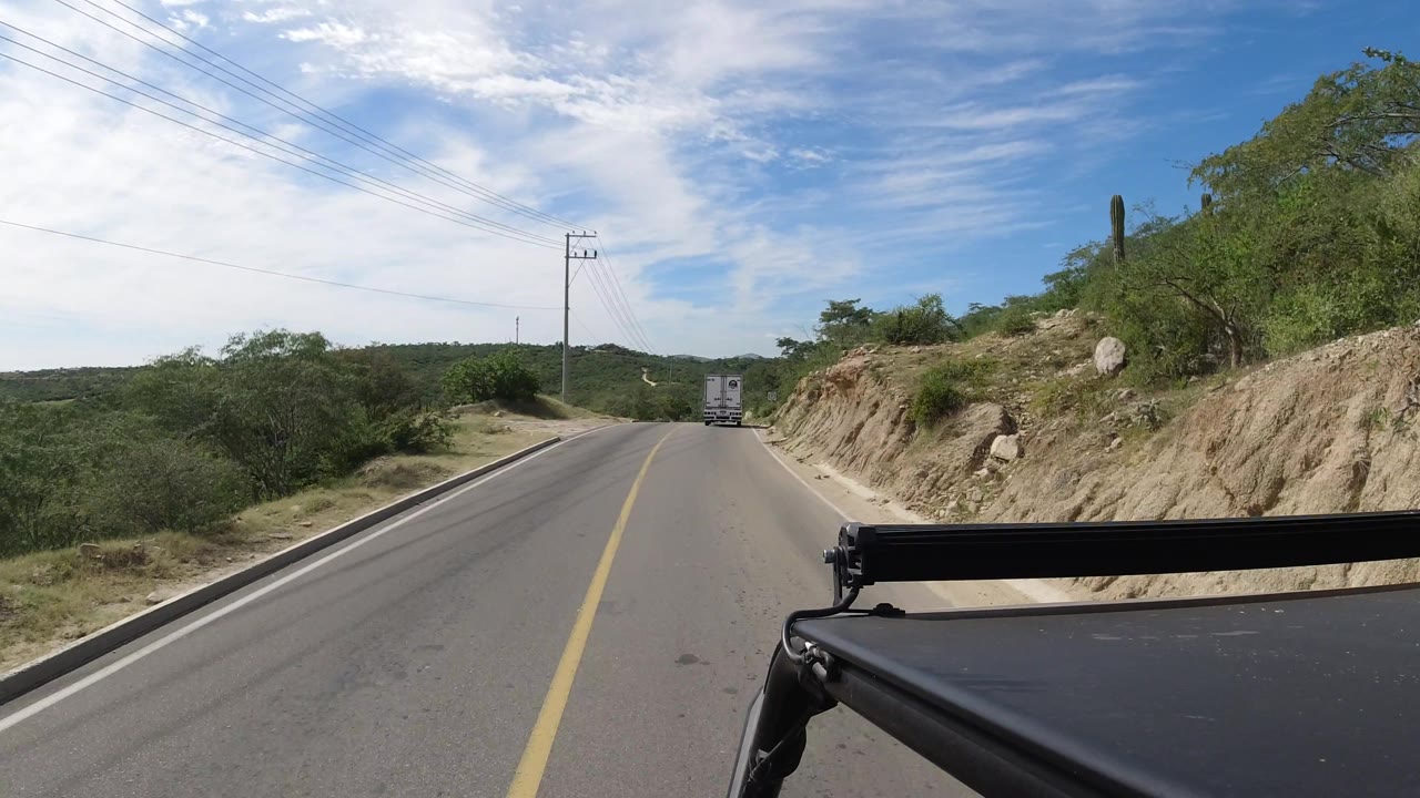 Truck ahead on a quiet road bordered by brush and rocks