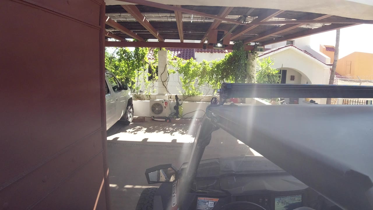 Dark SUV under a red gate in a sunny driveway