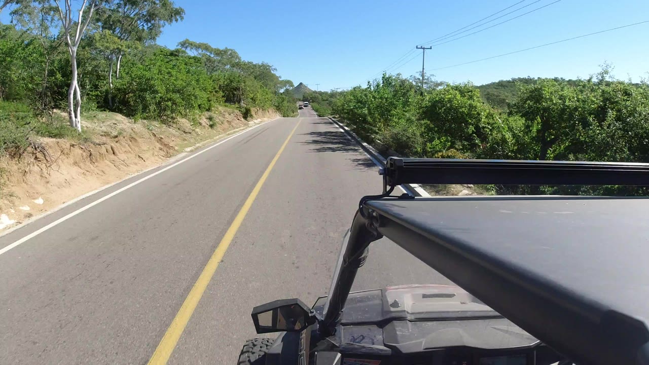 Forward road view from a Jeep on a sunlit two-lane highway.