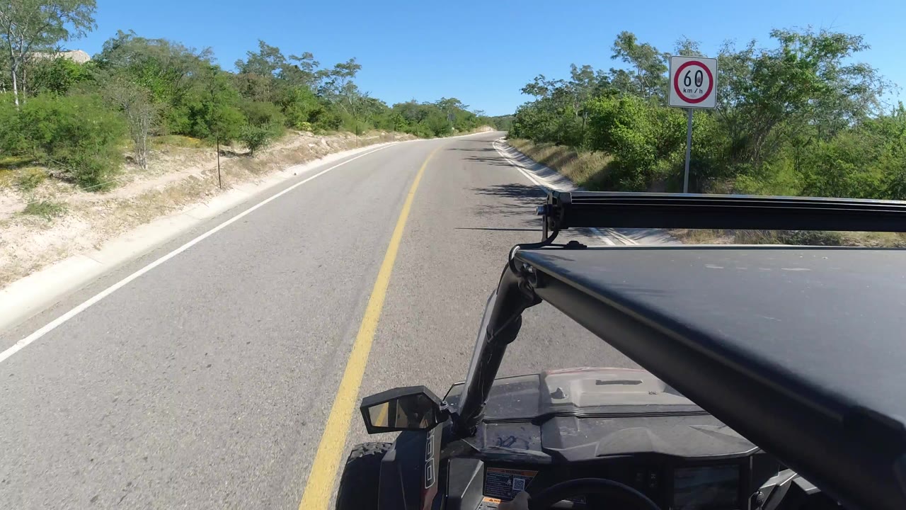 Vehicle POV on a paved road with trees and a speed sign.