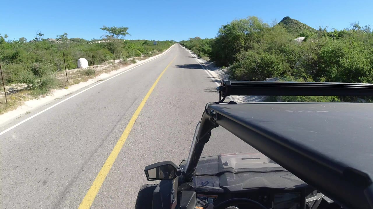 Forward view down a straight paved road from a vehicle roof.