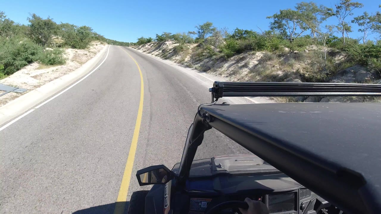Paved road ahead with vehicle hood and roof rack in foreground