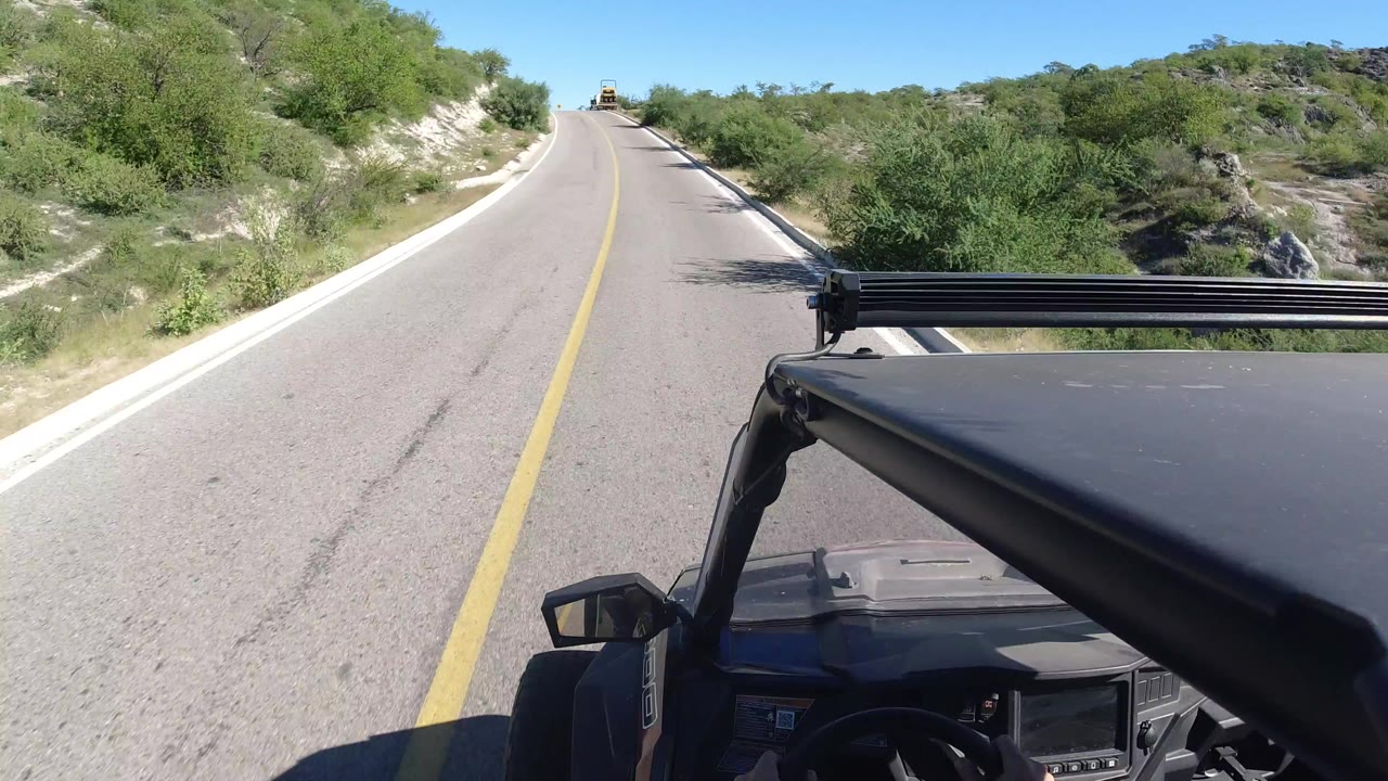 Vehicle POV on a paved road with trees and pale embankments