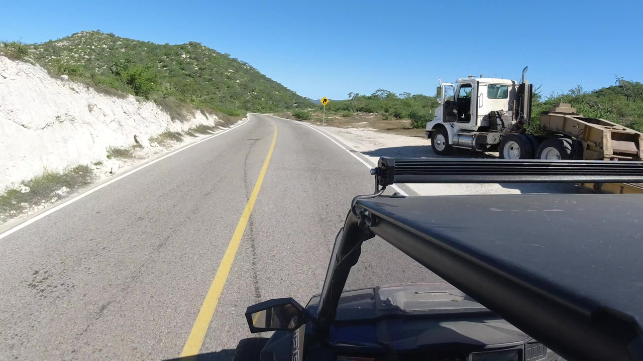 Curving road with a truck and trailer at the right edge of frame.