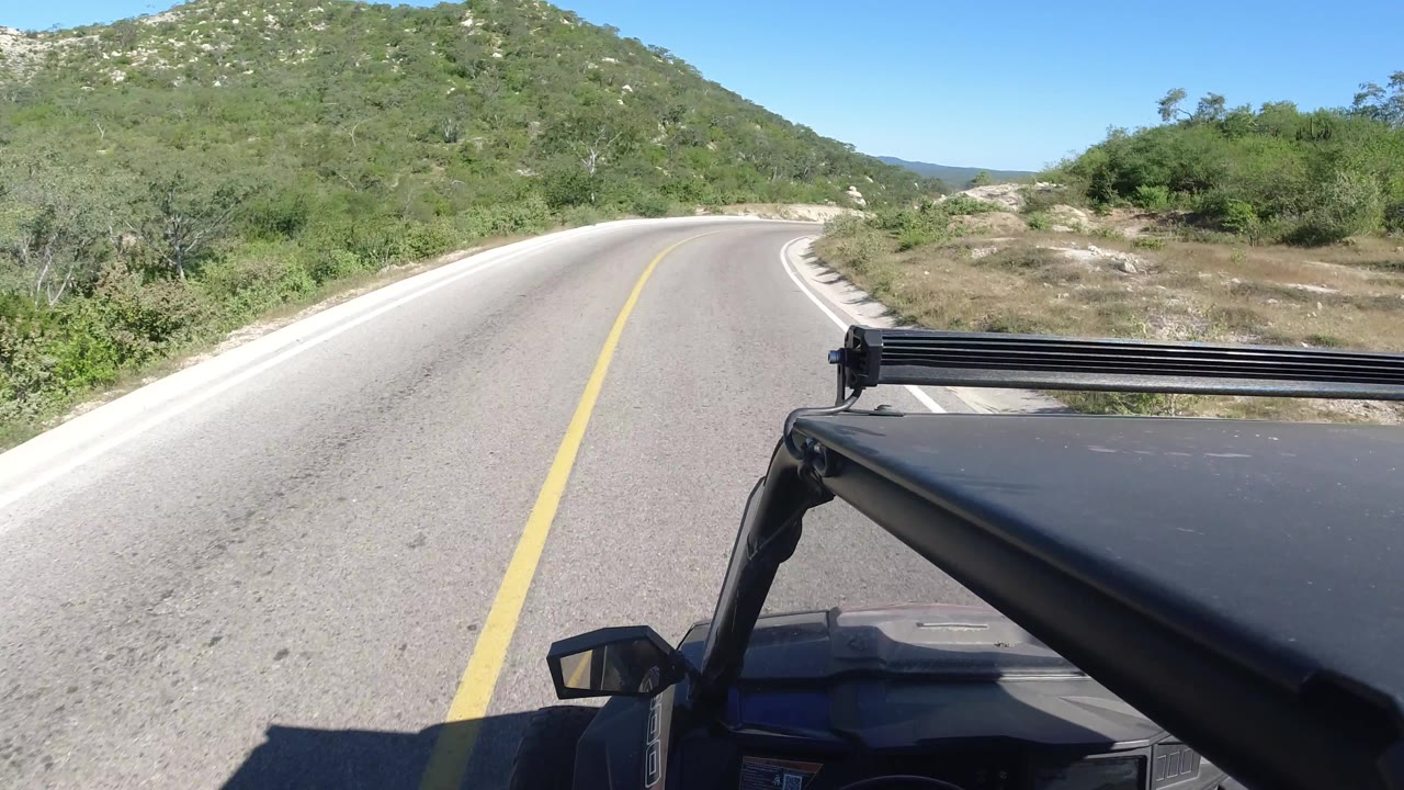 Mountain road bending right beside low scrub and rocks