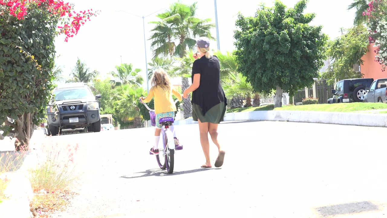 Adult woman walking beside a child on a small bicycle