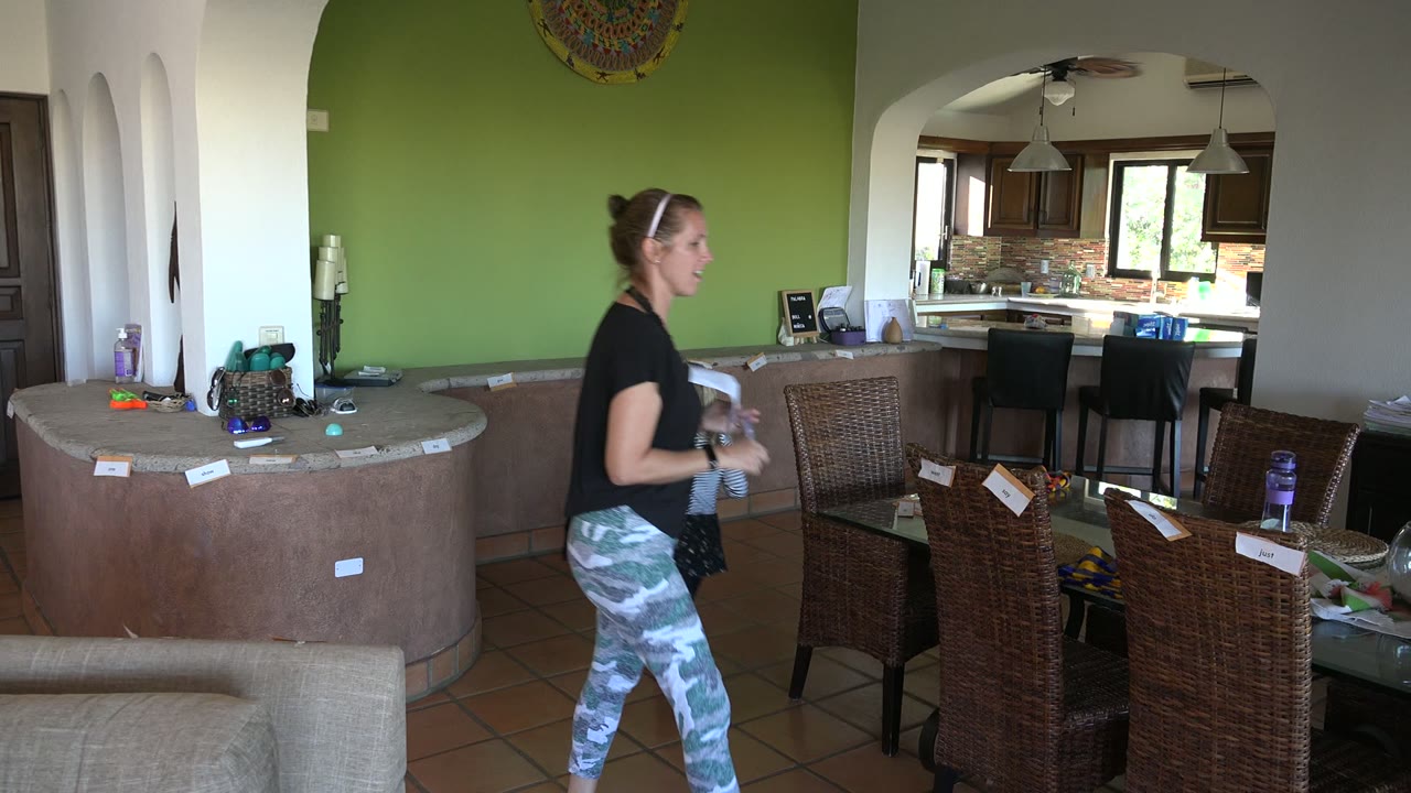Woman walking through dining room while a child is partly visible behind her.
