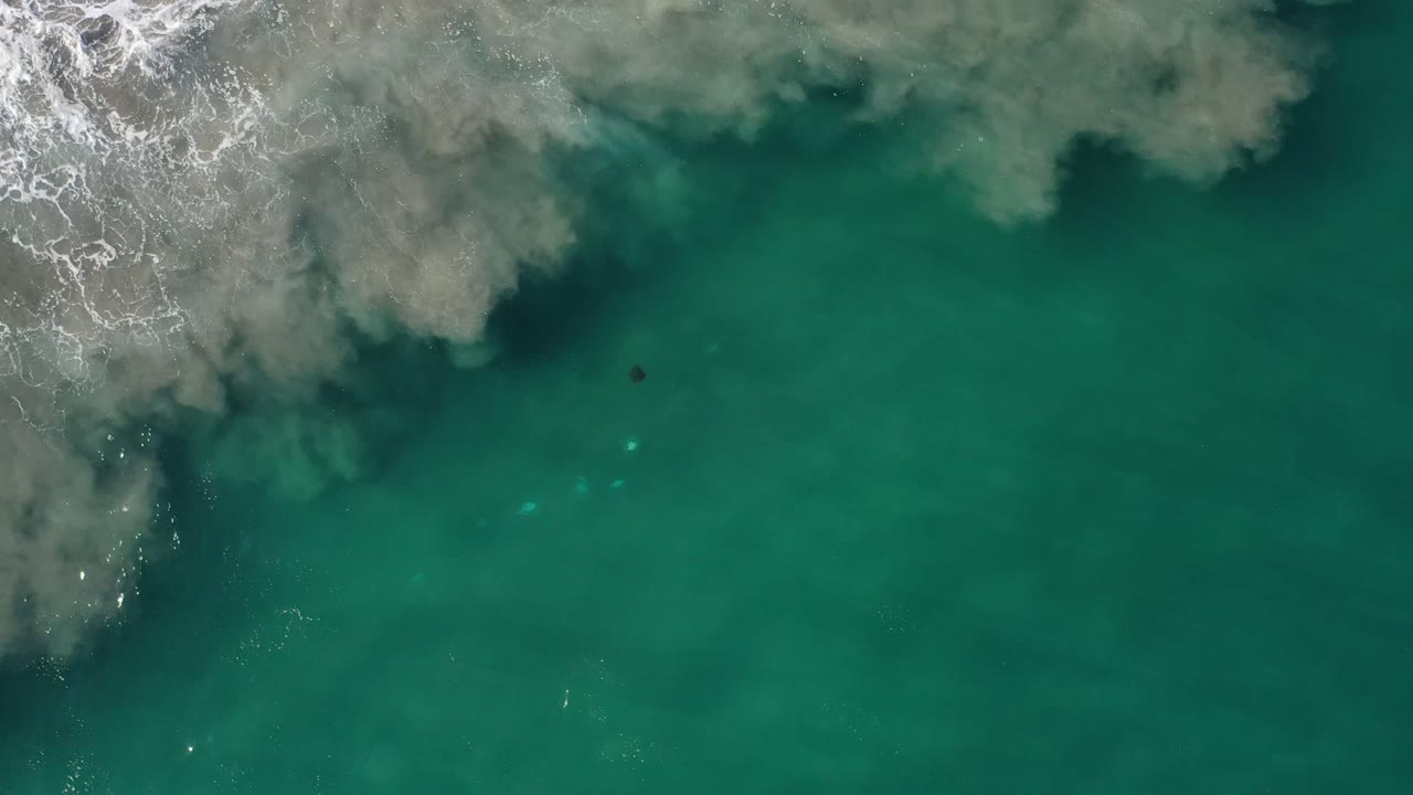 Overhead turquoise ocean with white surf and cloudy water plumes