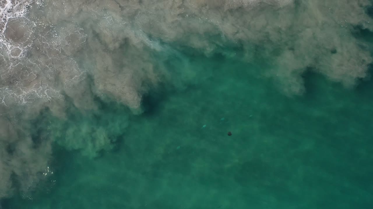 Overhead green ocean water with pale surf at the top edge.