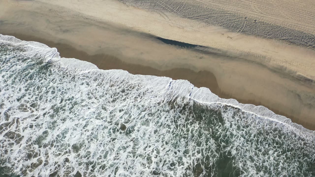 Overhead surf washing onto a sandy beach.