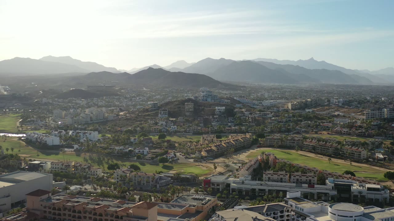 Wide aerial view of city, green grounds, and mountains