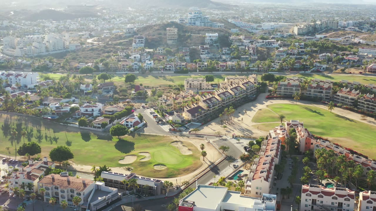 The second frame holds a wide Los Cabos view with clustered homes in the foreground, curved roads, green fairways, bunkers, hazy hills, and no visible people.