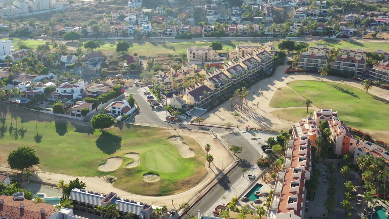 Aerial view of golf course greens, sand traps, roads, and red-roofed homes