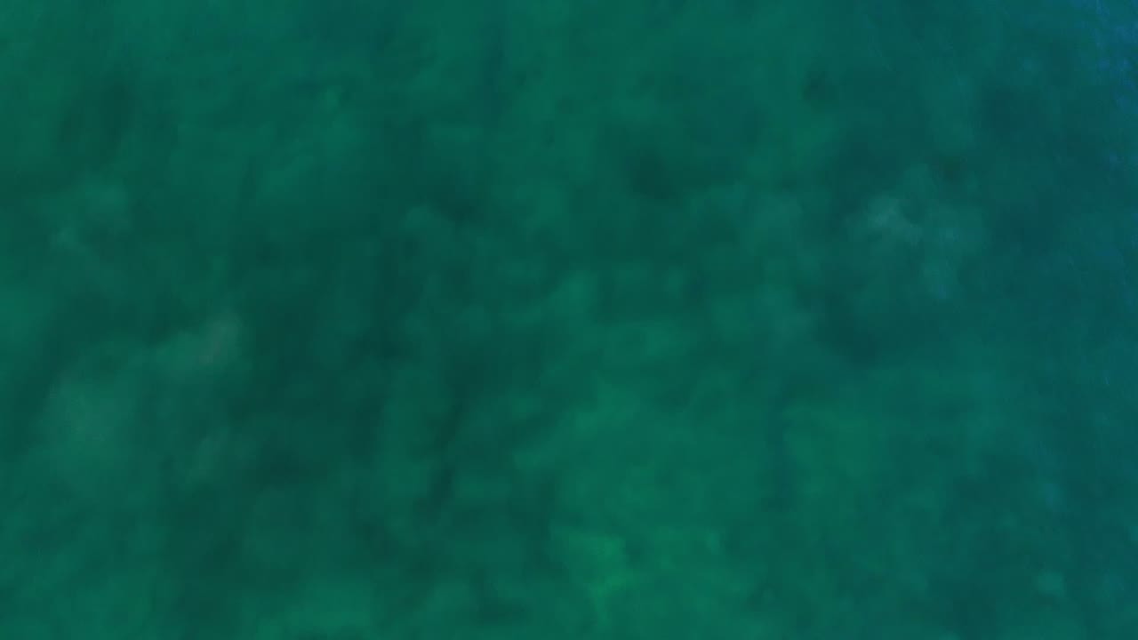 Teal Los Cabos water fills the frame from above, with faint ripple lines and no visible people.
