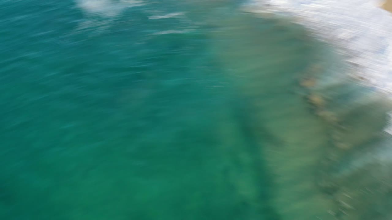 Turquoise ocean water with blurred white surf near the top edge.